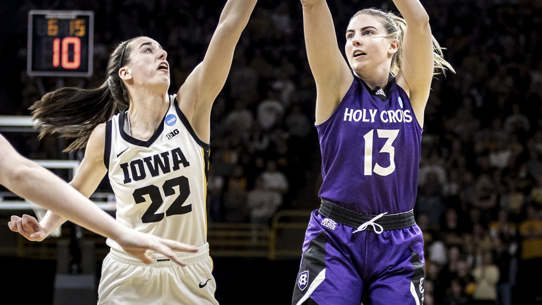 A Holy Cross women's basketball player on the right shoots over a player from Iowa on the left