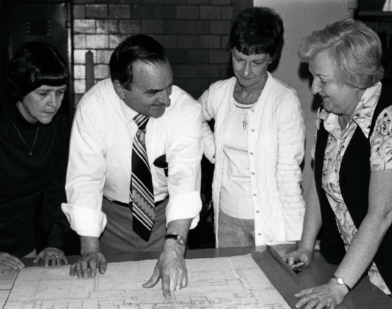 Black and white photo of people looking at blueprints